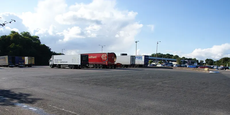 Des semi-remorques stationnées sur une grande aire de repos.