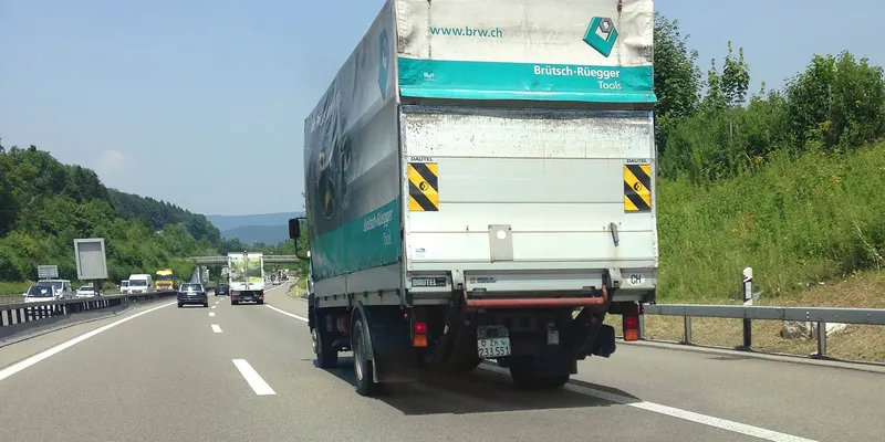Un camion porteur roule sur l’autoroute, vu de l’arrière.