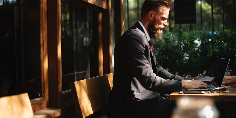 Un homme en costume travaille sur son ordinateur portable dans un café.